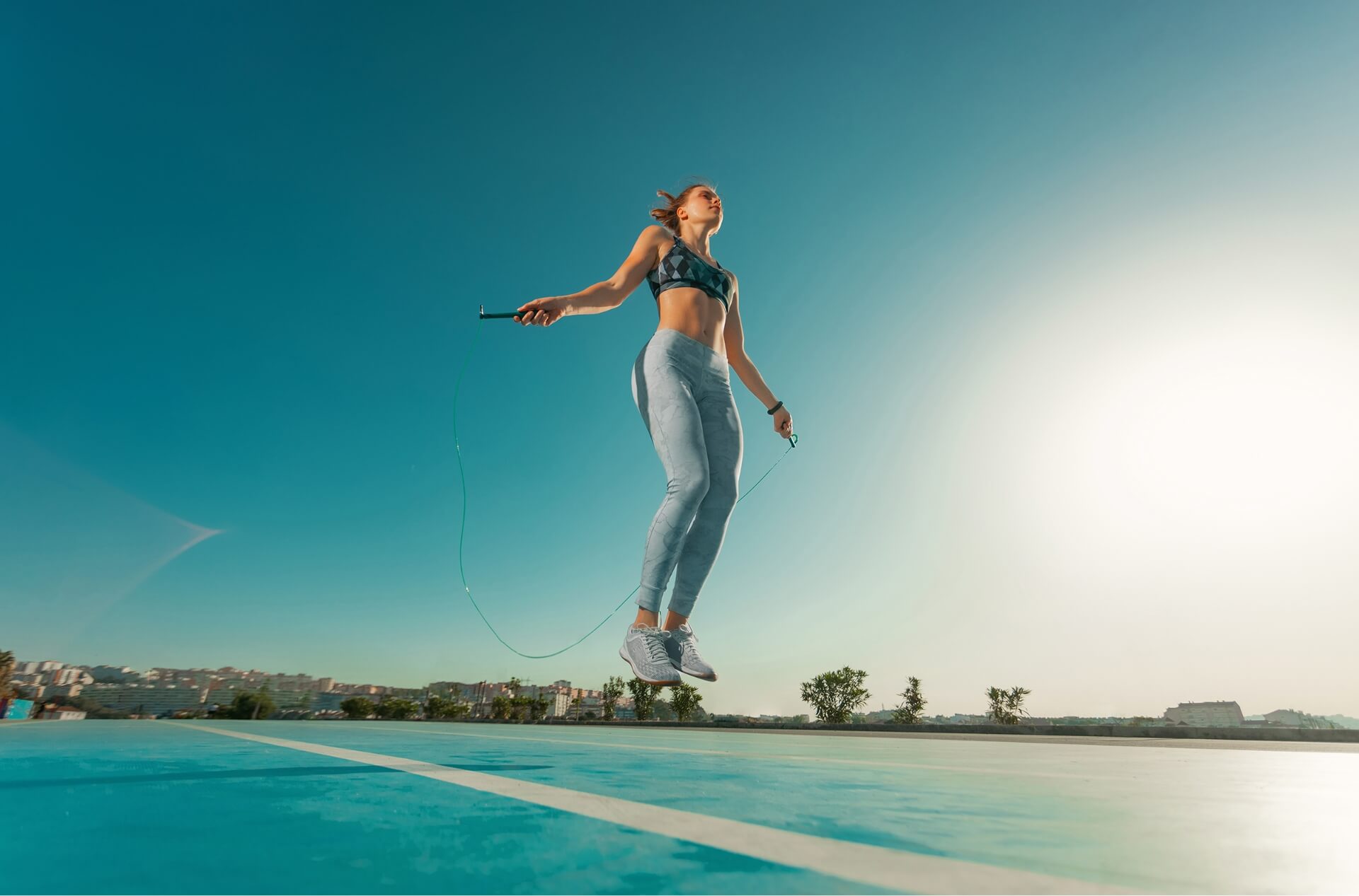 Young sportswoman training jumping agility ladder coordinating outdoors